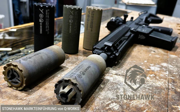 Q-WORKS Schalldämpfer und taktisches Gewehr auf Holztisch, Stonehawk Logo im Vordergrund